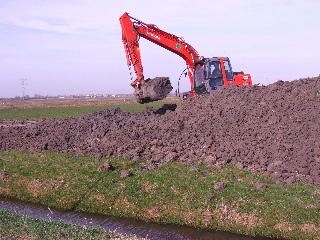 Graafmachine aan het werk met het ophogen van de inundatiekade.