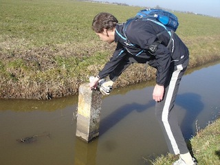 Martijn inspecteert het nummer van grenspaal O1.