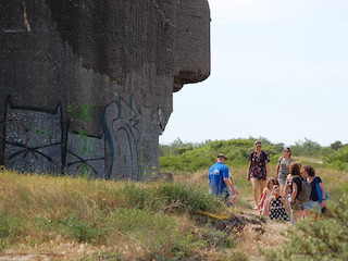 Bezoekers bij een bunker tijdens een rondleiding in de duinen van IJmuiden.