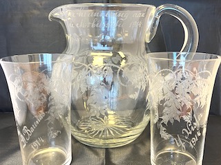 Waterkan en twee glazen met gegraveerde bloemenpatronen en namen.