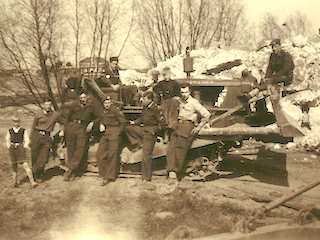 Bulldozer met militairen voor de resten van een remise op Fort Uitermeer.