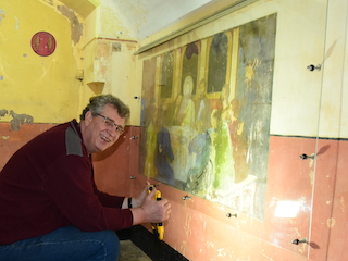 Onderzoeker René Ros heeft een zeldzaam plezier momentje bij het bestuderen van een muurschildering in het Fort bij Spijkerboor.
